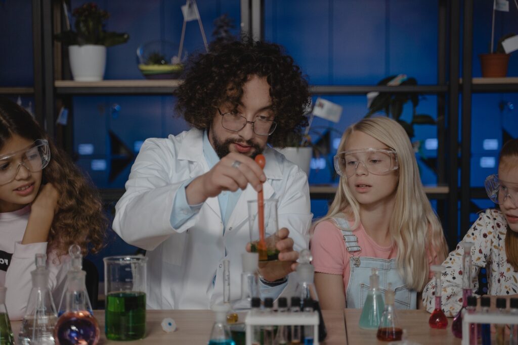 Teacher Mixing a Colored Liquid inside a Beaker