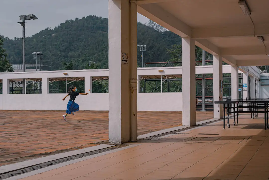 woman in blue shirt and blue denim jeans walking on brown wooden floor during daytime